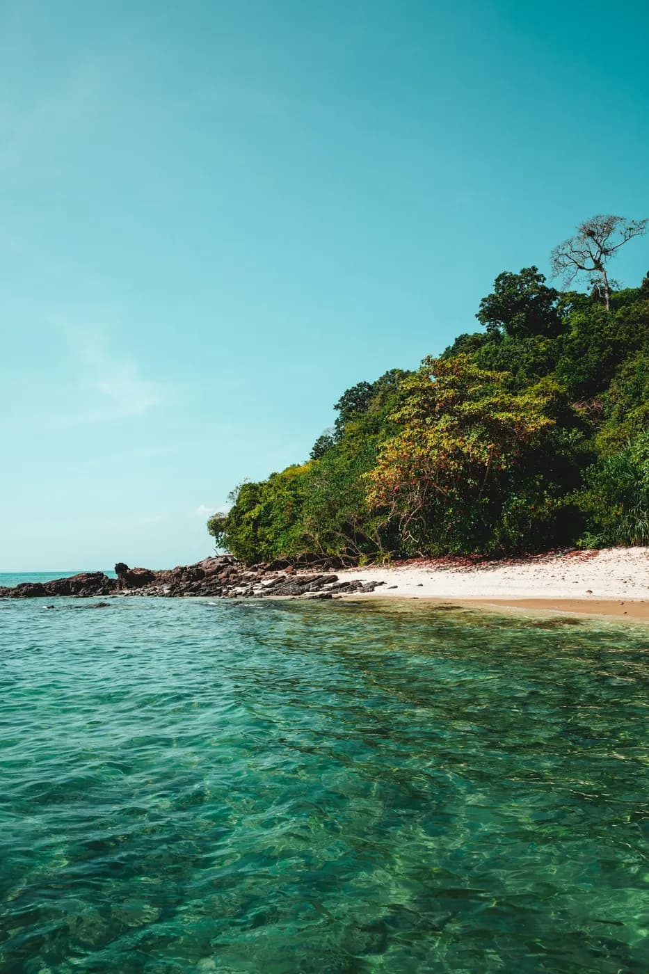 Clear shallow water over pale sand with an island beyond