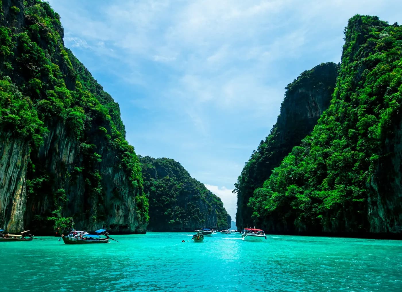 A longtail boat moored in an emerald cove between limestone walls