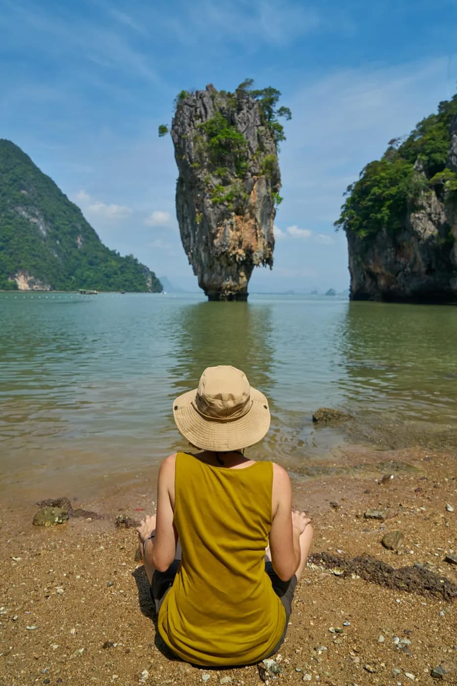 A person in a straw hat looking across a bay toward the cliffs