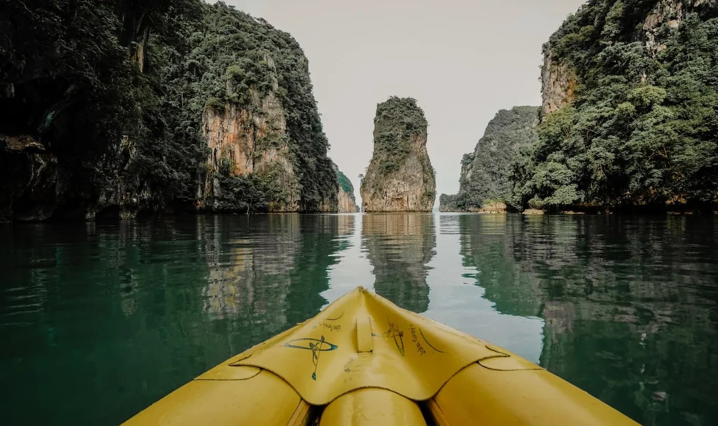 The bow of a yellow kayak pointed toward a limestone island