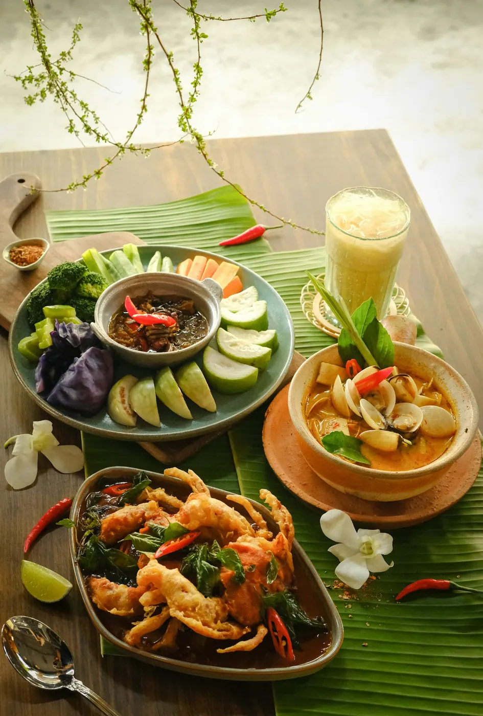 A spread of dishes and cold drinks on a wooden table
