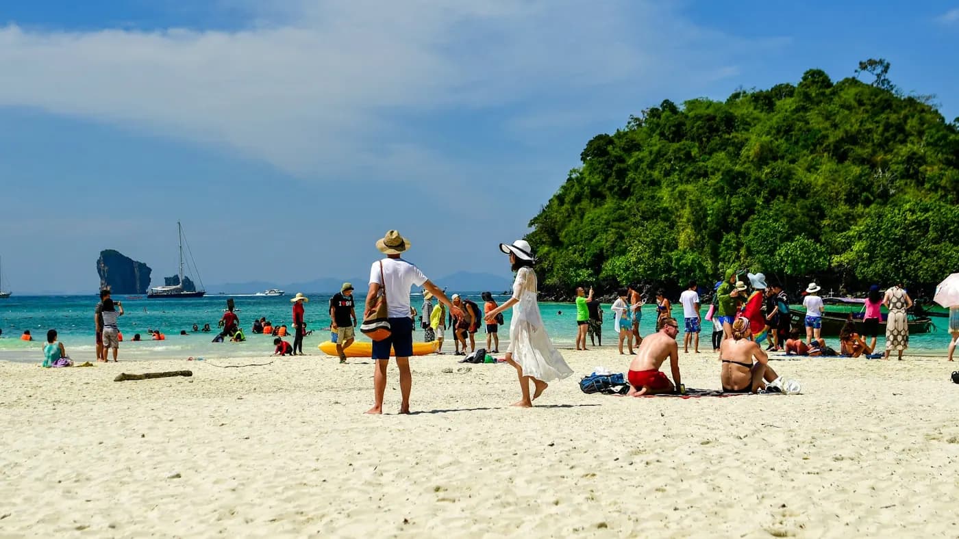 Swimmers and sunbathers along a wide white-sand beach