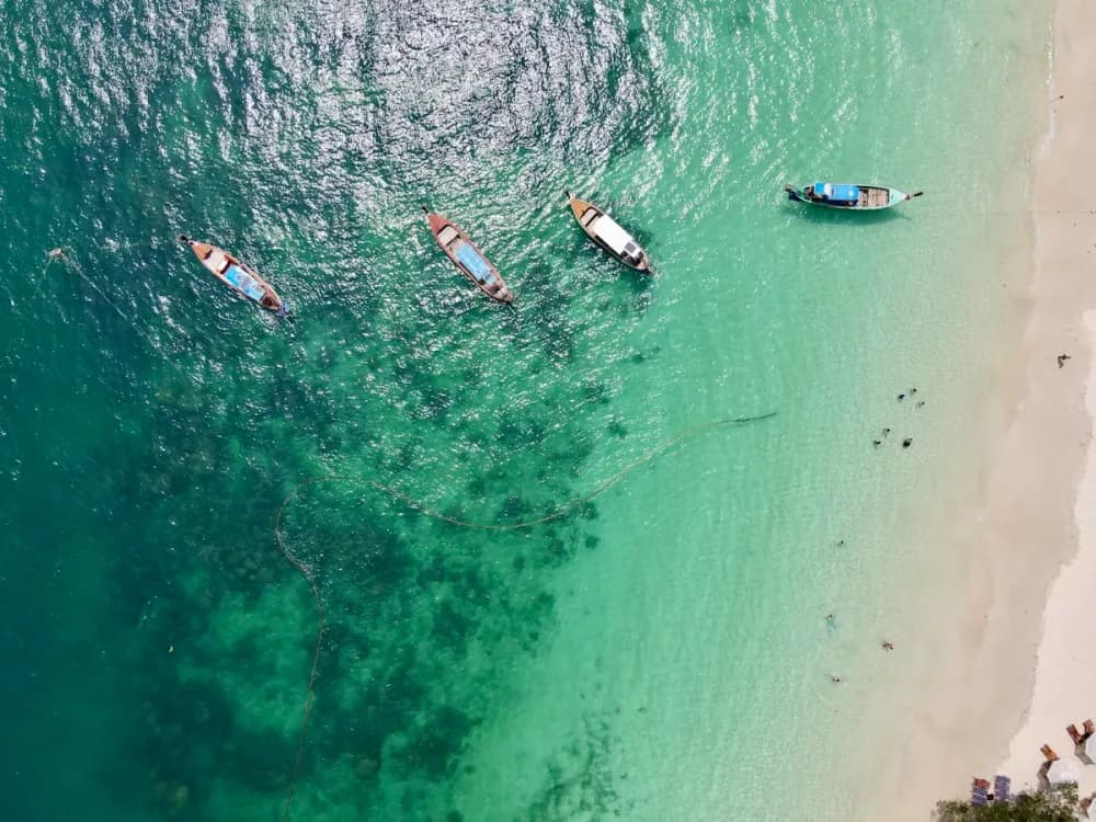 Longtail boats beside Coral Island’s shore off Rawai, Phuket